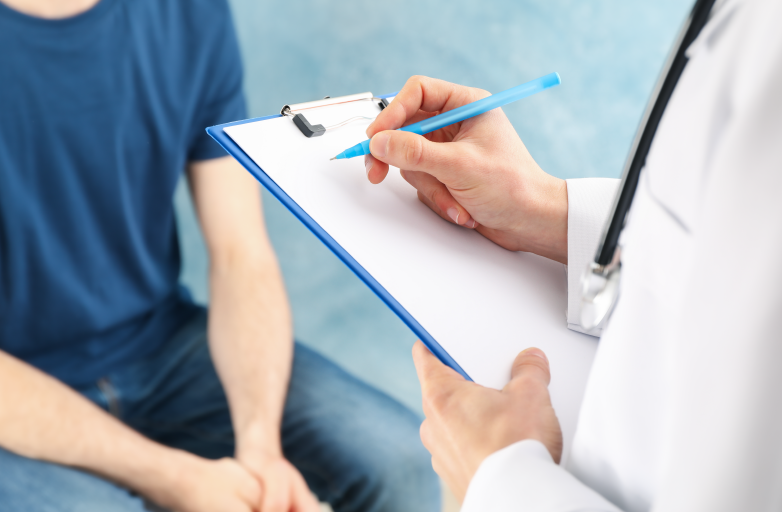 médico escribiendo en un portapapeles con un paciente sentado