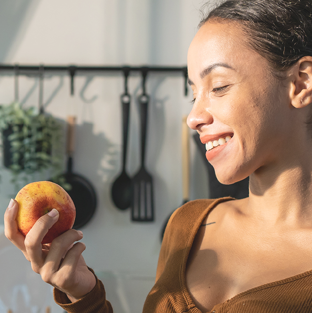 Mujer sonriendo con una manzana en la mano