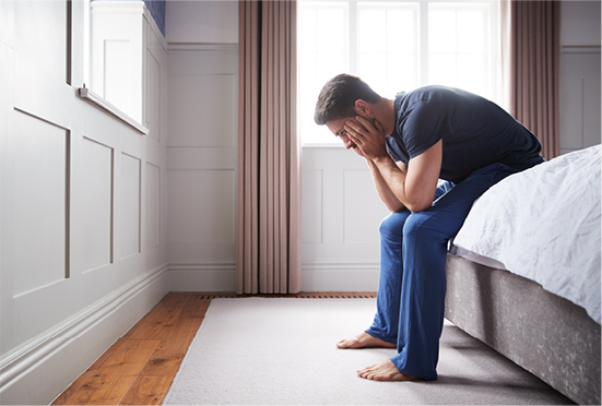 Hombre triste sentado en la cama con las manos en su cara